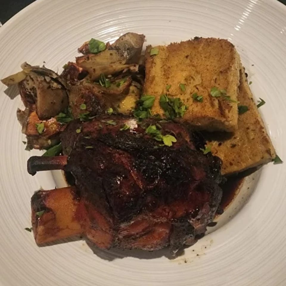Braised short rib with roasted potatoes and two slices of toasted bread, garnished with parsley.