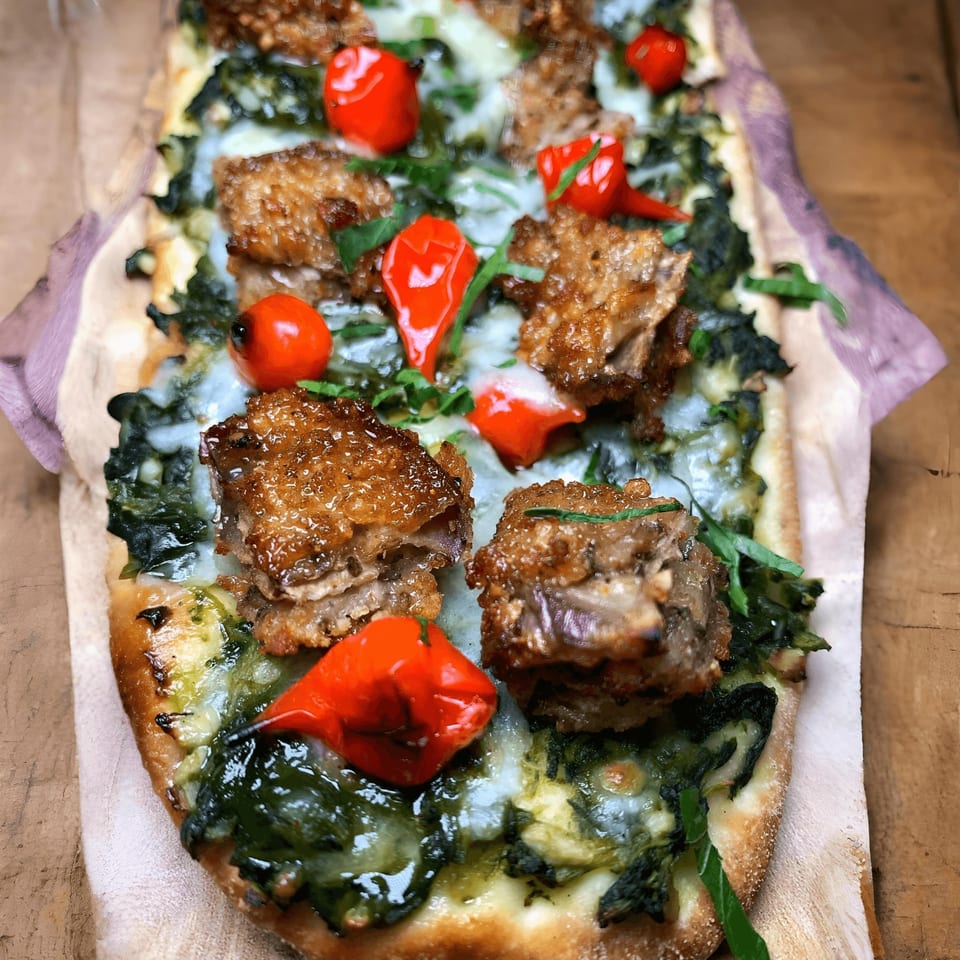 DaVinci & Yu's Asian-fusion flatbread with crispy pork belly, melted cheese, spinach, and red peppers.
